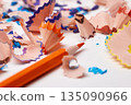 Orange pencil tip surrounded by colorful wood shavings on a white background 135090966