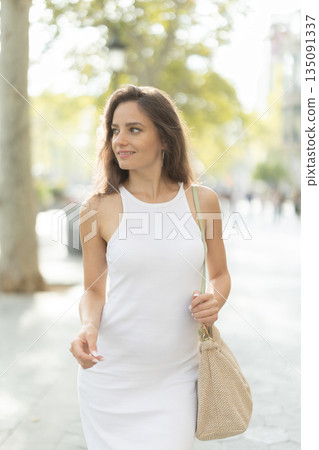 Young woman walks along city street Young woman walks along city street 135091337