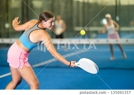 Portrait of girl paddle tennis player during friendly doubles couple match at court Portrait of girl paddle tennis player during friendly doubles couple match at court 135091357