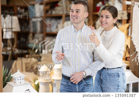 Positive young married couple choosing new garden furniture in furniture store Positive young married couple choosing new garden furniture in furniture store 135091387