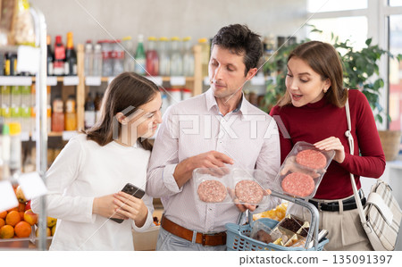 Family with teenage girl choosing hamburger in grocery 135091397
