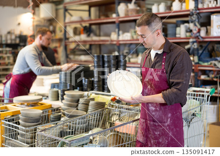 Young man posing with ceramic dishes Young man posing with ceramic dishes 135091417