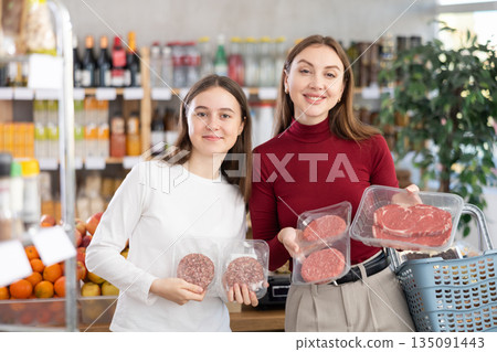 Teenage girl and her mother choosing hamburger or beef entrecote in grocery Teenage girl and her mother choosing hamburger or beef entrecote in grocery 135091443