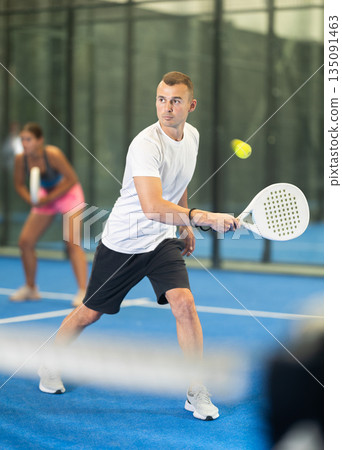 Young woman and man playing doubles tennis 135091463