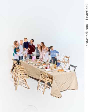 Warm multigenerational family gathering around festive dinner table. Warm multigenerational family gathering around festive dinner table. 135091469