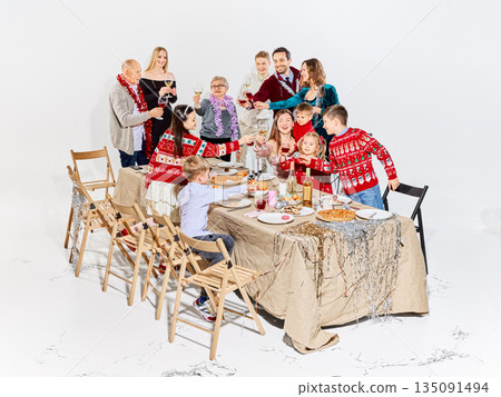 Festive family dinner scene with children and adults celebrating holidays. 135091494