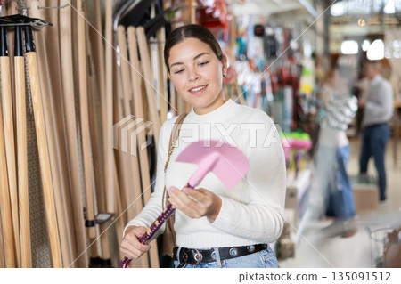 Young woman choosing shovel in store Young woman choosing shovel in store 135091512