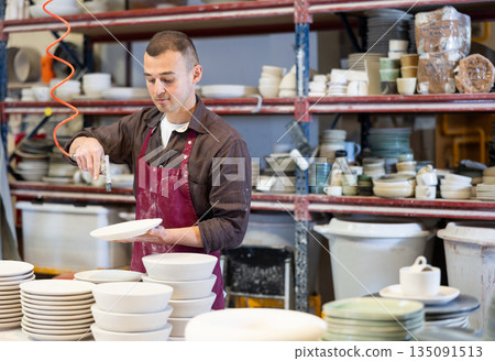 Ceramicist using air blow gun to remove dust from ceramics 135091513