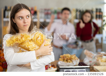 Daughter chose pile of potato chips in store, and quarrels with parents over choice of food Daughter chose pile of potato chips in store, and quarrels with parents over choice of food 135091526