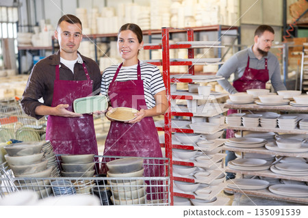 Artisan pair showcasing handcrafted ceramic plates in workshop 135091539