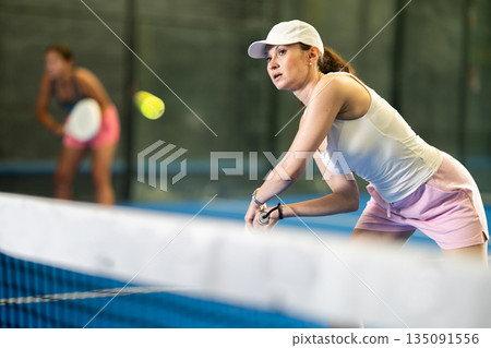 Woman playing padel on indoor court on summer day. Sport and active lifestyle concept 135091556
