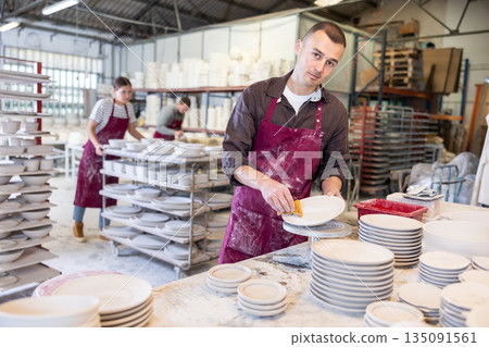 Ceramicist using sponge to clean pottery plates in artisanal workshop Ceramicist using sponge to clean pottery plates in artisanal workshop 135091561