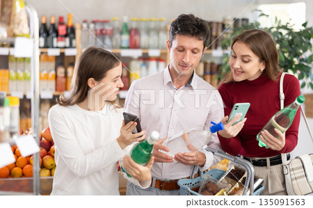 Family with teenage girl scanning QR on bottle of soda in supermarket Family with teenage girl scanning QR on bottle of soda in supermarket 135091563