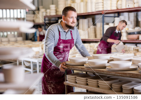 Artisan pushing cart laden with ceramic wares for drying 135091586