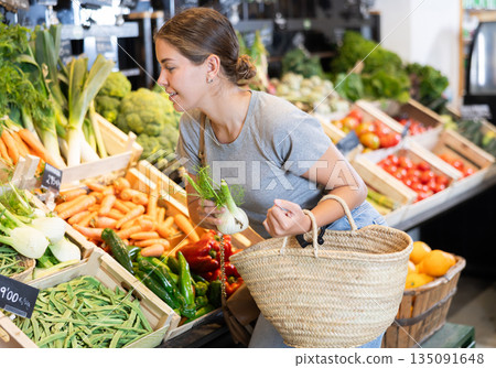 In vegetable department of bio supermarket, female customer took daikon radish from window 135091648