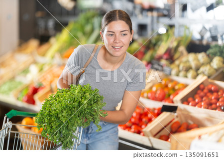 Young girl purchaser buying bunch of fresh parsley in grocery store 135091651