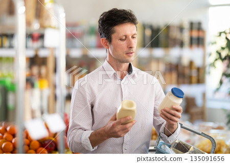 Adult man choosing mayonnaise in grocery store Adult man choosing mayonnaise in grocery store 135091656