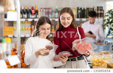 Woman with daughter chooses hamburger or entrecote Woman with daughter chooses hamburger or entrecote 135091658