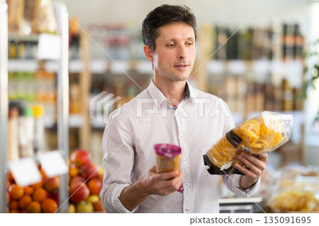 Man in light shirt choose and buy pasta in store Man in light shirt choose and buy pasta in store 135091695