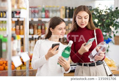 Mom and daughter scanning soda bottles 135091706