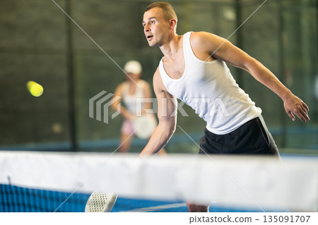 Active man with enthusiasm playing padel on tennis court 135091707