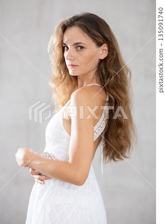 Young serious woman posing against wall background Young serious woman posing against wall background 135091740