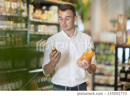 Man in supermarket buys bottle of drink 135091773