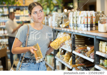 Girl choosing pasta in natural grocery section of supermarket 135091907