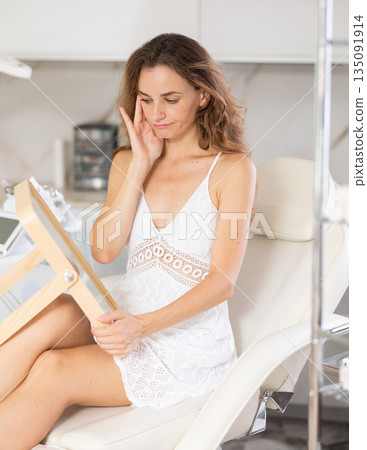 examining her reflection with satisfaction 135091914