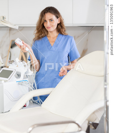 Young woman doctor posing with cosmetology apparatus Young woman doctor posing with cosmetology apparatus 135091963