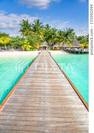 Tranquil relaxing wooden pier pathway into tropical island paradise sunny beach landscape turquoise ocean calm water palm trees sunny sky Maldives luxury summer vacation travel tourism background 135092094
