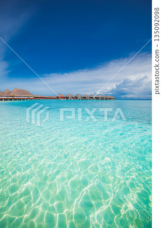 Stunning Maldives ocean lagoon with turquoise water overwater villas in luxury resort popular summer vacation sunshine horizon peaceful blue sky tropical seascape exotic island getaway background 135092098