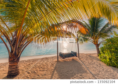 Tropical beach paradise with palm trees swing over soft sand peaceful sunset and sunrise ocean view remote summer vacation destination tourism scenic background tropical island getaway 135092104