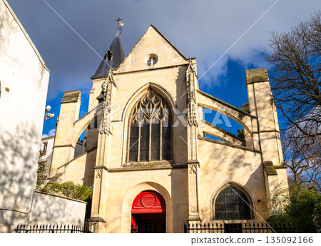Church of Saint Medard stands in Paris, France. Historic Gothic architecture features a stone facade with flying buttresses and a bright red door near Rue Mouffetard 135092166