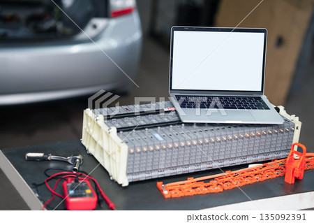 Serviceman repairs electric battery pack of hybrid car using laptop 135092391