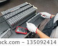 Serviceman repairs electric battery pack of hybrid car 135092414
