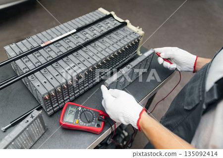 Serviceman repairs electric battery pack of hybrid car 135092414