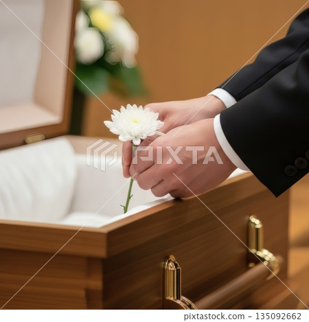 葬禮上，一名身著喪服的男子將告別鮮花放入棺材中。 135092662