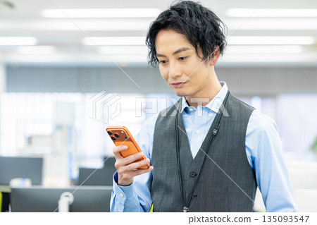 一名男子正在操作最新智慧型手機 一名男子正在操作最新智慧型手機 135093547