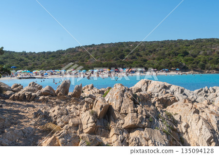 Rocky beach overlooking a calm bay with turquoise water. Natural coastal scenery on a bright summer day, ideal for travel, vacation and outdoor lifestyle imagery, La Maddalena, Italy Rocky beach overlooking a calm bay with turquoise water. Natural coastal scenery on a bright summer day, ideal for travel, vacation and outdoor lifestyle imagery, La Maddalena, Italy 135094128
