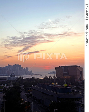 Vibrant sunset paints the sky over a modern cityscape and waterfront buildings 135094571