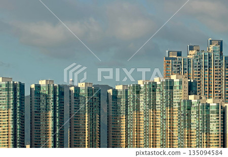 Modern high-rise apartment buildings with glass facades under cloudy sky 135094584