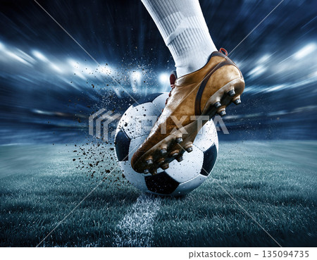 Soccer player kicks ball during match in stadium with bright lights and cheering crowd in evening hours 135094735
