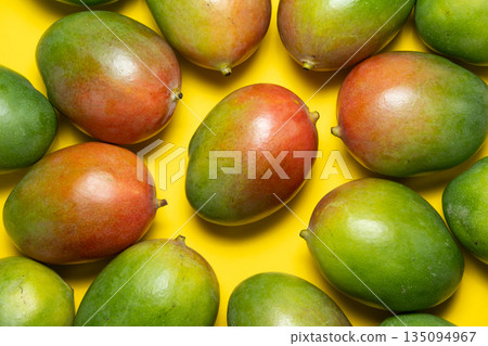 Composition of fresh mangoes on yellow surface. 135094967