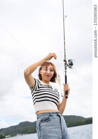 A woman smiling as she shows off the fish she caught. (Photo courtesy of Oki Seaside Resort Miyabi) 135095063