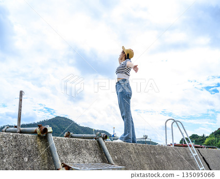 A woman with her arms outstretched on the embankment (Photo courtesy of Oki Seaside Resort Miyabi) A woman with her arms outstretched on the embankment (Photo courtesy of Oki Seaside Resort Miyabi) 135095066
