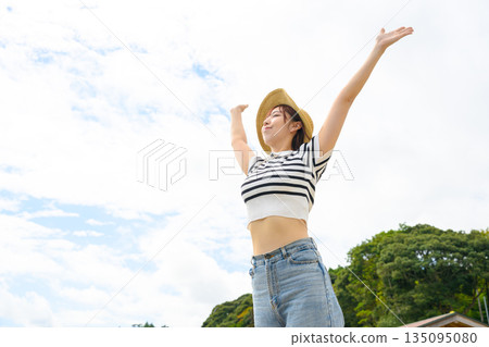 A woman with her arms outstretched under the blue sky [Photography cooperation: Oki Seaside Resort Miyabi] 135095080