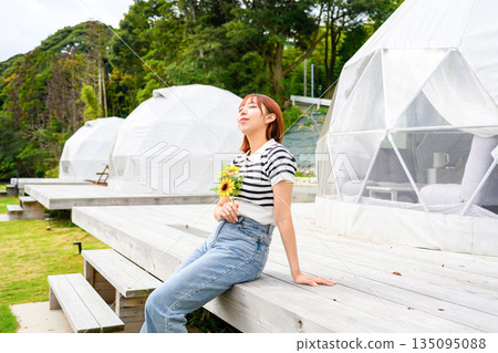 A woman sunbathing with a sunflower (Photo courtesy of Oki Seaside Resort Miyabi) A woman sunbathing with a sunflower (Photo courtesy of Oki Seaside Resort Miyabi) 135095088