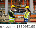Two industrial worker wearing safety helmet and reflective vests shake hands inside manufacturing factory, symbolizing teamwork, trust collaboration successful industrial. accept approve agreement. 135095165