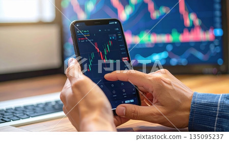 Hand holding a remote control for watching television, with a finger pressing the channel button on the digital keypad 135095237